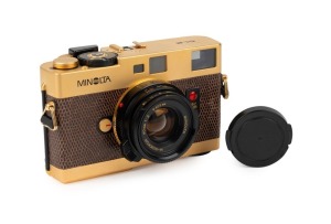 MINOLTA: Gold-edition Minolta CLE rangefinder camera [#2000400] with brown lizardskin covering, c. 1981, with M-Rokkor 40mm f2 lens [#2120649] and lens cap.