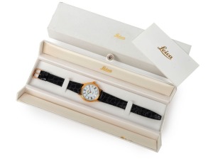 LEITZ: Swiss-made, fully-jeweled Leica gold-plated wristwatch with stainless-steel back and reptile-skin strap, in white and gold presentation box with warranty card and cardboard protective sleeve.