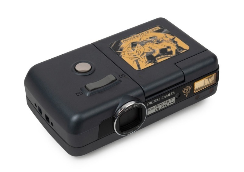 RIKEN: Limited-edition 'Principality of Zeon' DC-3G digital camera [#300246], c. 1998, in grey with Ricoh 5-15mm f3.8 lens together with maker's box, data cable, and SmartMedia card. Featuring gold imagery from the Gundam Japanese animation franchise, the