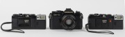 CHINON: Three c. 1980 35mm cameras - one&nbsp;CM-4s SLR&nbsp;with Auto Chinon 50mm f1.9 lens [#752977], together with two&nbsp;Bellami compact cameras [#237164 & #184665], both with wrist straps and with one maker's box/instruction booklet/case present. (3 cameras)