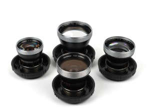 CARL ZEISS: Four c. 1950s Contaflex Pro-Tessar lenses in plastic domes with front lens caps - one 35mm f3.2 [#4684189], one 35mm f4 [#2357491], one 85mm f4 [#1878081], and one 115mm f4 [#3981570]. (4 items)