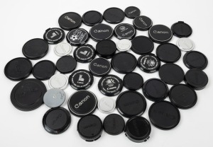 CANON: A mixed assortment of thirty-two black plastic and twelve metal front and rear lens caps, of various diameters. (44 items)