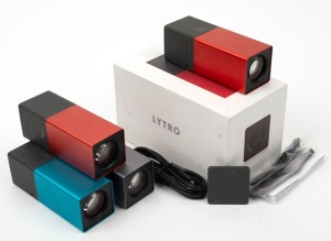 LYTRO: Two c. 2012 Lytro light field cameras - one in red [#A302150287] in maker's box and one in graphite [#A102111307], together with one red and one blue dummy display model. (4 items)