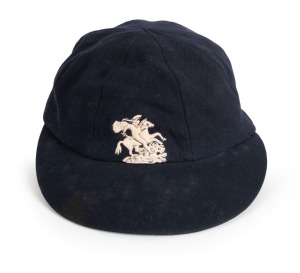 1965-66 ASHES SERIES IN AUSTRALIA: English Cricket Cap in deep blue with embroidered 'St George and the Dragon' on the front, worn by English fast bowler Jeff Jones during the series and exchanged with Graham McKenzie. The name "I.J.Jones" is hand-written on the Simpson of Piccadilly maker's label; good condition overall. Jeff Jones took 6 for 118 in the Fourth Test and was England's top wicket taker for the series with 15 scalps.