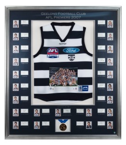 GEELONG CATS: 2007 Premiership display featuring a commemorative Grand Final jersey surrounded by photographs of all team members and their original signatures (23 total); complimented by a replica Premiership medal and A-tag certification number 03018236. Framed and glazed, overall 119 x 104cm.