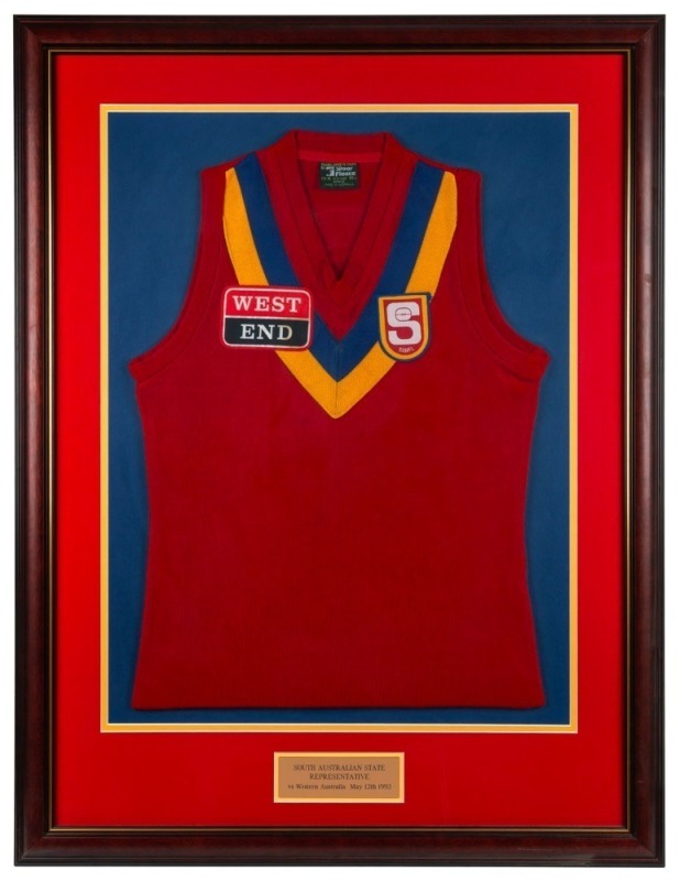 South Australian State Representative guernsey worn by Nathan Buckley while representing the SANFL in a game against the WAFL played on May 12 1992. Framed & glazed.This was not a State of Origin contest but a game played between representative sides from