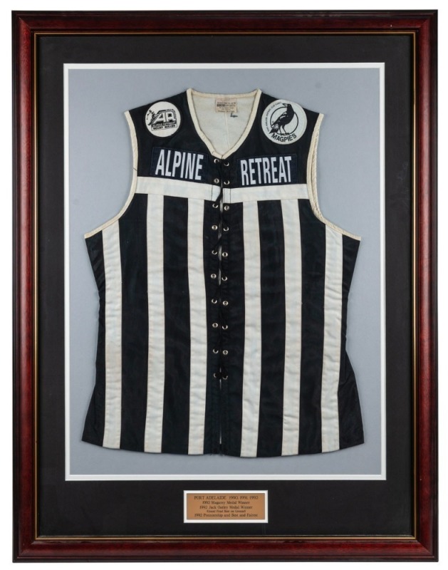 Port Adelaide lace-up guernsey worn by Nathan Buckley in the 1992 SANFL Grand Final, in which Port defeated Glenelg by 56 points. Framed & glazed. Buckley won the Jack Oatey Medal for being best on ground in that game, completing a barnstorming season in