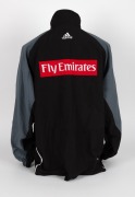 Nathan Buckley’s Collingwood players’ jacket circa 2001-02. Black adidas jacket with full zip, adidas logo on right breast, Collingwood logo on left breast, above small red Emirates patch. Black front with grey sleeves and white striping/highlights. Large - 4