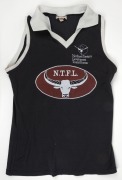 NTFL representative training guernsey, c1992. Black with white collar and edging. Oval NTFL badge in centre of jumper, ochre with steer horns. NT Government Tourist Bureau badging. 2 examples issued to Nathan Buckley. - 2