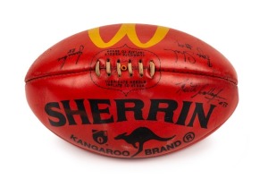 100th GAME FOOTBALL: A red Sherrin football with yellow McDonald’s logo that has been signed by umpires Bryan Sheehan (#9), Jamie Love (#28, '96-99) and Keith Callaghan #33 who were in charge for Buckley's 100th career game, Collingwood v Fremantle in 199