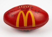 100th GAME FOOTBALL: A red Sherrin football with yellow McDonald’s logo that has been signed by umpires Bryan Sheehan (#9), Jamie Love (#28, '96-99) and Keith Callaghan #33 who were in charge for Buckley's 100th career game, Collingwood v Fremantle in 199 - 2