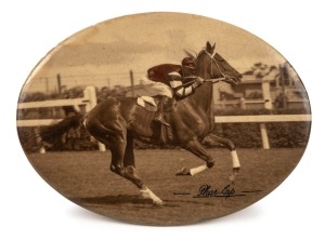 PHAR LAP: A small celluloid tin-plate oval depicting the classic image of jockey, Jim Pike riding Phar Lap at Flemington Racecourse, sometime in 1930. The sepia image has been carefully enhanced to reflect the correct colours of Pike's  jacket. Overall 93