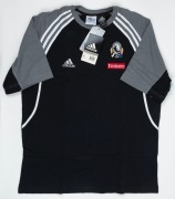 Collingwood T-shirt/training top, early 2000s. Black shirt with adidas logo on right breast and Collingwood logo on left breast, above small red Emirates patch. White stripes and grey sections on sleeves/shoulders. First issued 2001. (2 examples; one worn - 2