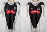 Collingwood training/T-shirts, circa 2006. White with black front and black stripes on sleeves. Red &lsquo;Fly Emirates&rsquo; patch across middle, with adidas and Collingwood logos above. Wizard logo to rear of one. (2 items).