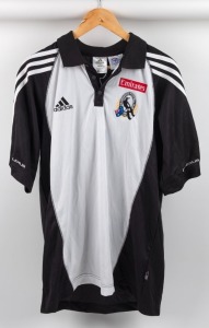 Collingwood players’ polo, circa 2006. White front with black sleeves with three white stripes on sleeves, adidas logo on right breast, red Emirates on left above Collingwood logo. Lexus on sleeves.