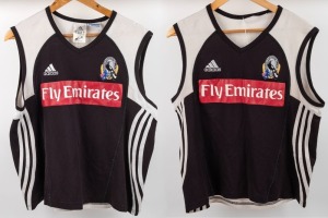Nathan Buckley Collingwood training tops, circa 2006; black fronts with red Fly Emirates patch, adidas and Collingwood logos above, cut away shoulders with white highlights, V-neck. Stripes along sides and Wizard logo on the backs. Two examples, one in quite worn condition. (2).