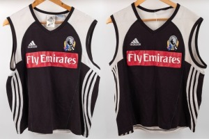 Nathan Buckley Collingwood training tops, circa 2006; black fronts with red Fly Emirates patch, adidas and Collingwood logos above, cut away shoulders with white highlights, V-neck. Stripes along sides and Wizard logo on the backs. Two examples, one in qu