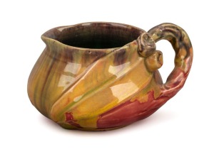 REMUED pottery jug with applied gumnuts, leaf and branch handle, unusual pink, mauve and mustard glaze with green interior, incised "Remued", 7cm high, 13cm wide