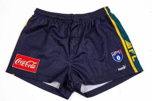 International Rules series v Ireland 1998. Nathan Buckley’s playing shorts from the games against Ireland in 1998. Dark blue with green and gold piping along the sides, with red Coca Cola patch and AFL logo.