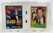 Group of newspaper/magazine pages with images and/or stories about Nathan Buckley. All have been pre-framed: positioned behind glass and mounted to foam board, but not yet framed. Plus Collingwood 2016 team poster, and photo page from Football Record shoo