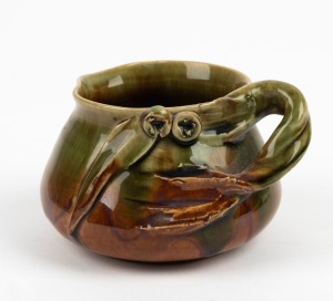 REMUED pottery jug with applied gumnuts, leaf and branch handle, glazed in green and brown, incised "Remued", 7.5cm high, 12cm wide