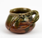 REMUED pottery jug with applied gumnuts, leaf and branch handle, glazed in green and brown, incised "Remued", 7.5cm high, 12cm wide