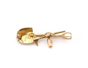 GOLD MINING BROOCH: Crossed pick and shovel adorned with several gold nuggets and a bucket, South African, 19th century. 4 grams.