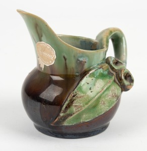 REMUED pottery jug with applied gumnuts, leaf and branch handle, glazed in brown and green with grey interior, incised "Remued, Hand Made", with original foil label, 10.5cm high