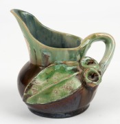 REMUED pottery jug with applied gumnuts, leaf and branch handle, glazed in brown and green with grey interior, incised "Remued, Hand Made", with original foil label, 10.5cm high - 2