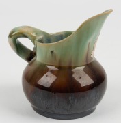 REMUED pottery jug with applied gumnuts, leaf and branch handle, glazed in brown and green with grey interior, incised "Remued, Hand Made", with original foil label, 10.5cm high - 4