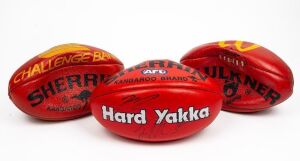 Group of three full-size match footballs, from the early-to-mid 2000s. Two are red Sherrins, one with Collingwood logo and Yakka branding that has been signed by two unknown persons and the other with Challenge Bank branding. The third ball is a red Ross 