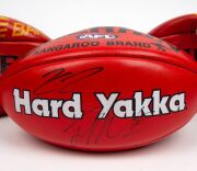 Group of three full-size match footballs, from the early-to-mid 2000s. Two are red Sherrins, one with Collingwood logo and Yakka branding that has been signed by two unknown persons and the other with Challenge Bank branding. The third ball is a red Ross - 2