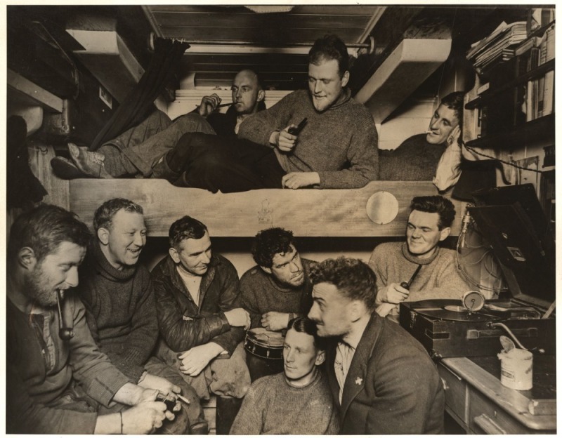 THE B.A.N.Z. ANTARCTIC EXPEDITION:Official original photograph by Captain Frank Hurley:Image A27 - Title: Explorers entertained in Antarctica,with official "MAWSON ANTARCTIC EXPEDITION" handstamp and release date "TUESDAY APR.15, 1930" verso,20 x 26cm.