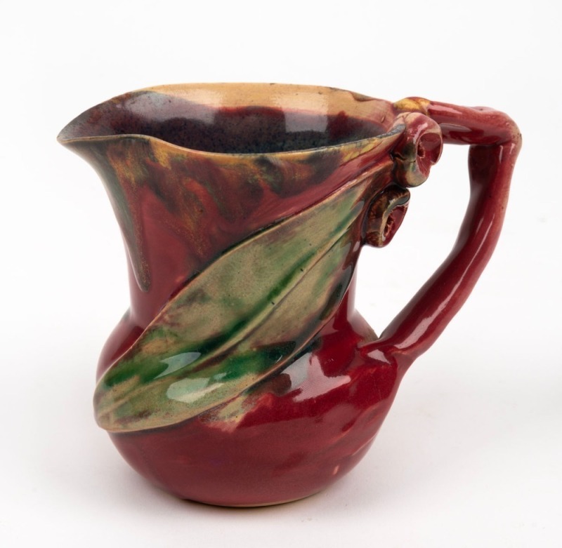 REMUED pottery jug with branch handle, gumnuts and leaf, glazed in a rich pink and green with yellow highlights, incised "Remued", ​​​​​​​11cm high