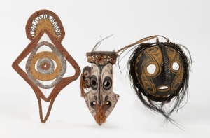 Two tribal masks and a woven ornament, carved wood, fibre, feather and painted finish, Papua New Guinea origin, (3 items), the largest 33cm high