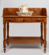 An antique Australian huon pine washstand with well figured birdseye splash back, two drawers and lower shelf, with accompanying wash basin and water jug with floral decoration made by Briar & Sons, Tasmanian origin, circa 1860, (3 items), the washstand 9