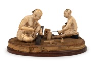 An antique Chinese carved ivory figural group of two seated craftsman, Qing Dynasty, early to mid 19th century, ​​​​​​​10cm high, 20cm wide