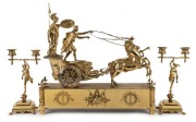 An antique French brass-cased figural mantle clock with chariot scene, eight day time and bell striking movement with applied enamel Roman numerals, retailed by HOWARD & Co. of New York, late 19th century, together with a pair of figural candelabra garnit