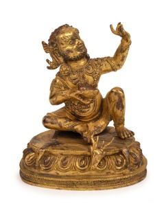 A finely cast Tibetan gilt bronze seated statue of a bearded figure with thick eyebrows and tightly curled wearing necklaces and large circular earrings, seated on a single lotus base with an animal skin mat, 18th/19th century, ​​​​​​​15cm high