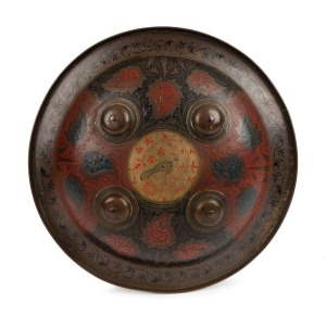 VERY ORNATE PERSIAN BRASS SHIELD: 11” in diameter; deeply curved with 4 central domed brass bosses; black foliage surround to the rim; gold central panel with a large bird with red & black foliage designs to the surface of the shield; with a lacquered fin