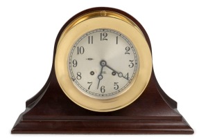 CHELSEA BULKHEAD ship's clock in brass case with silver dial with Arabic numerals, sounding the watch bells, mounted on later mahogany mantle case, 20th century, 25cm high overall