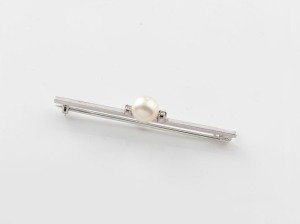 An 18ct white gold bar brooch, set with a cultured pearl flanked by a pair of brilliant cut white diamonds, mid 20th century, 7.5cm wide, 3.9 grams