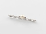An 18ct white gold bar brooch, set with a cultured pearl flanked by a pair of brilliant cut white diamonds, mid 20th century, ​​​​​​​7.5cm wide, 3.9 grams