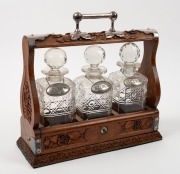 An antique English three bottle&nbsp;tantalus, carved oak with silver plated mounts and labels, 19th/20th century, ​​​​​​​35cm high