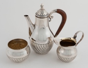 A vintage sterling silver bachelor three piece coffee set with remains of gilt wash interior, consisting of a small coffee pot, milk jug and sugar bowl, circa 1930, stamped "925" with pictorial marks, the coffee pot 19cm high, 580 grams total (including wooden handle)