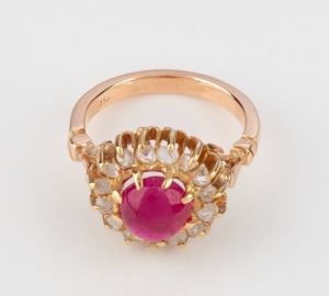 An 18ct yellow gold ring, set with a cabochon ruby surrounded by white diamonds, stamped "750", 6.5 grams