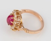 An 18ct yellow gold ring, set with a cabochon ruby surrounded by white diamonds, stamped "750", ​​​​​​​6.5 grams - 2