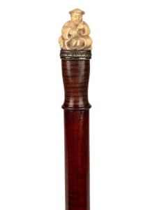 A walking stick with Chinese carved ivory seated figure handle on a fiddleback snakewood shaft with brass ferrule, 86cm high