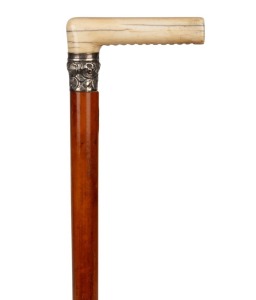 An antique walking stick with carved ivory handle, embossed silver collar, Malacca cane shaft and brass ferrule, 85cm high