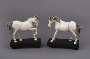 A pair of antique Chinese carved ivory horse statues, late 19th early 20th century, on lacquered stands, 13cm high, 13cm wide overall